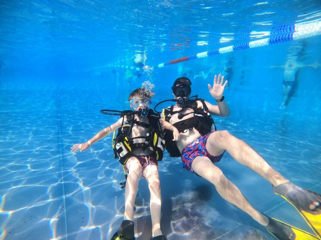Am Rücken Liegend winkende Taucher Vater und Sohn